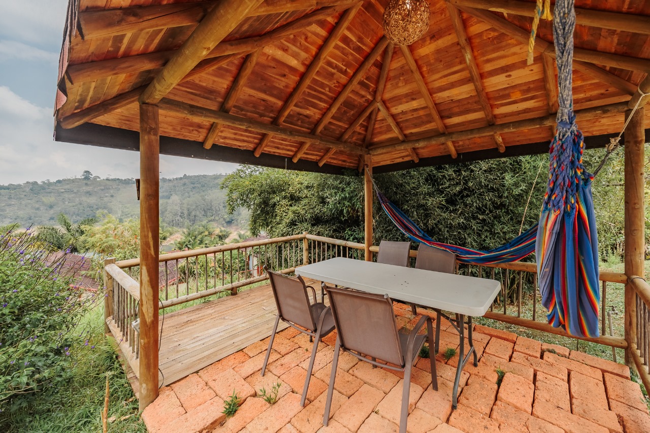 Kiosco de madera con hamaca y mesa frente a la montaña