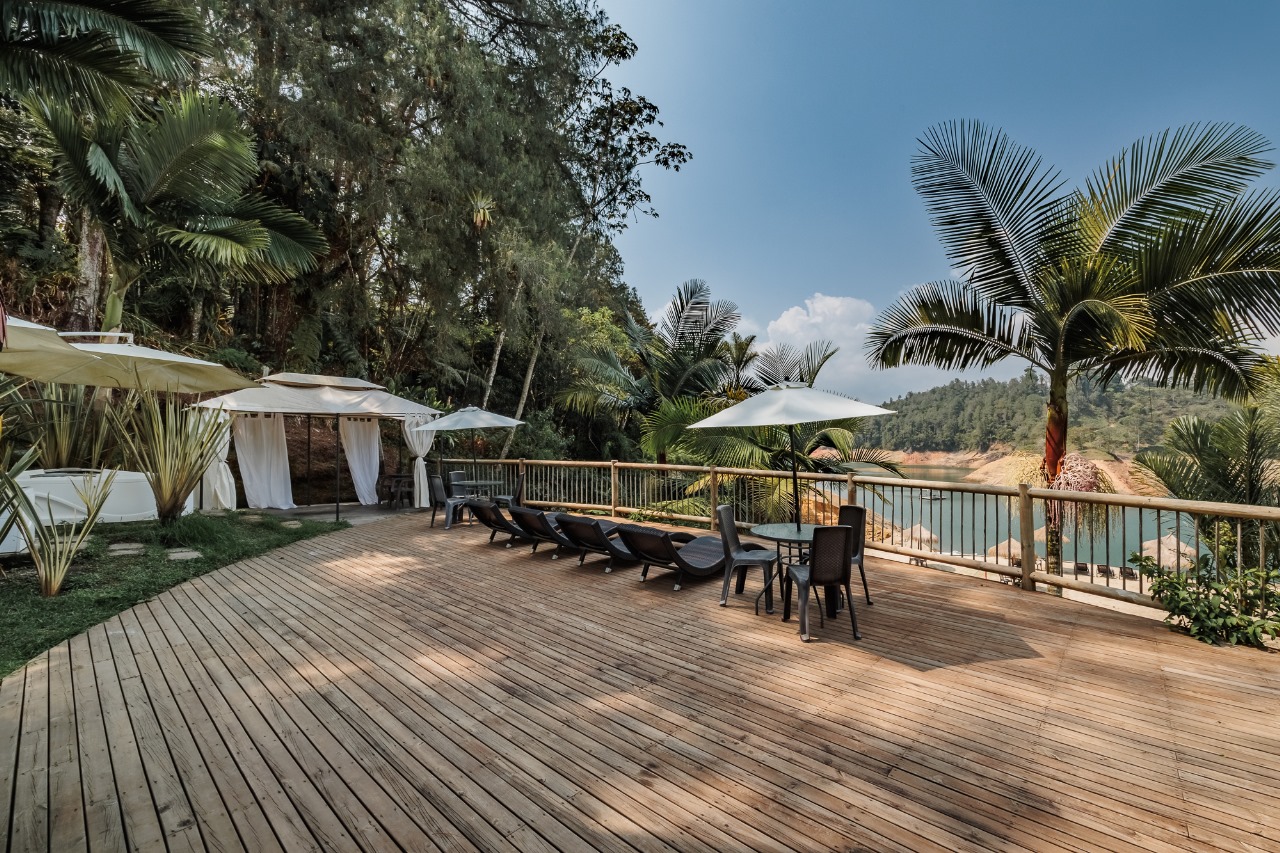 Terraza de madera con reposeras y sombrillas frente al embalse