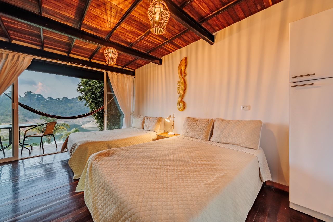 Habitación con dos camas, hamaca y vista al embalse al amanecer